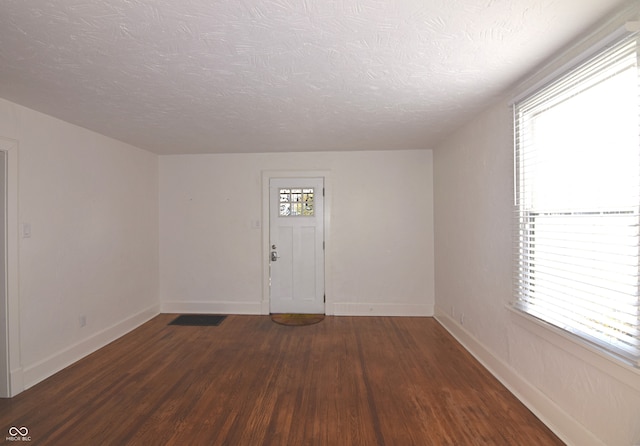 interior space with plenty of natural light, dark wood-type flooring, and a textured ceiling