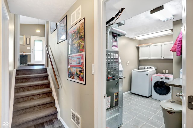 laundry room with light tile patterned flooring, cabinets, and washer and dryer