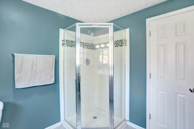 bathroom featuring a textured ceiling and a shower with shower door