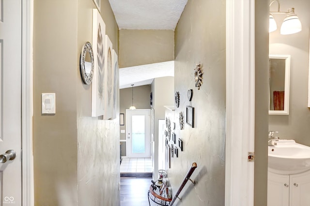 hallway featuring a textured ceiling, hardwood / wood-style floors, and sink