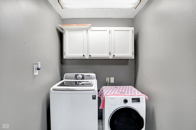 clothes washing area featuring cabinets and washer and dryer