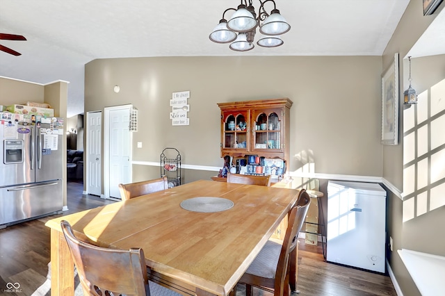 dining area featuring ceiling fan with notable chandelier, dark wood-type flooring, and vaulted ceiling