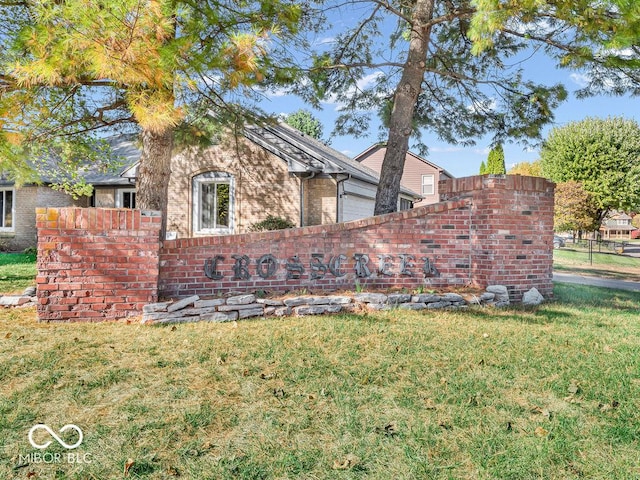 exterior space featuring brick siding, fence, and a front lawn