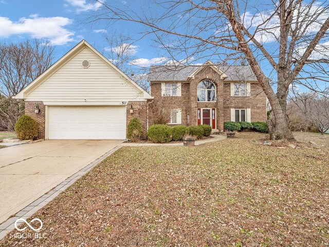 colonial inspired home featuring concrete driveway, brick siding, and a garage