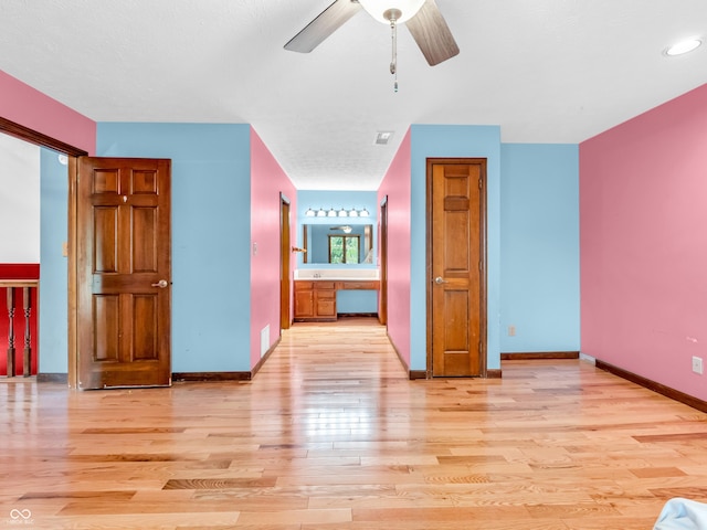interior space featuring light wood finished floors, a ceiling fan, visible vents, and baseboards