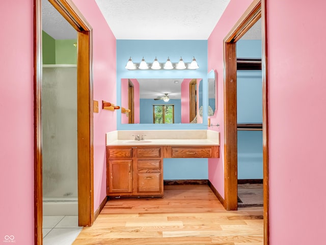 bathroom featuring wood finished floors, a shower stall, and vanity