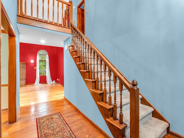stairs featuring a towering ceiling, hardwood / wood-style flooring, and baseboards