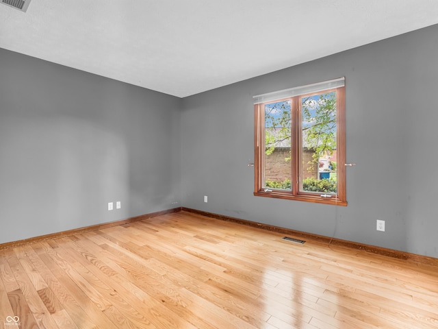 empty room featuring visible vents, wood finished floors, and baseboards