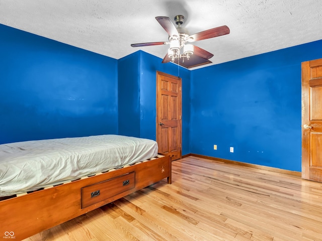 bedroom featuring baseboards, ceiling fan, a textured ceiling, and light wood-style flooring