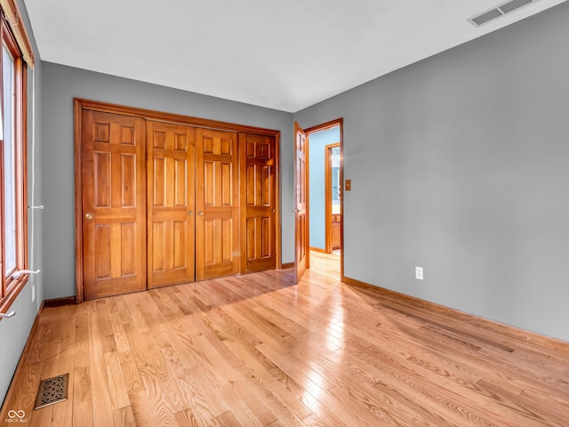unfurnished bedroom with visible vents, light wood-style flooring, and baseboards