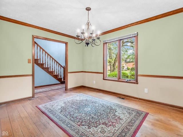 spare room featuring an inviting chandelier, baseboards, hardwood / wood-style flooring, and visible vents