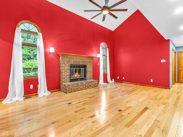 unfurnished living room with visible vents, a fireplace, wood finished floors, a ceiling fan, and high vaulted ceiling