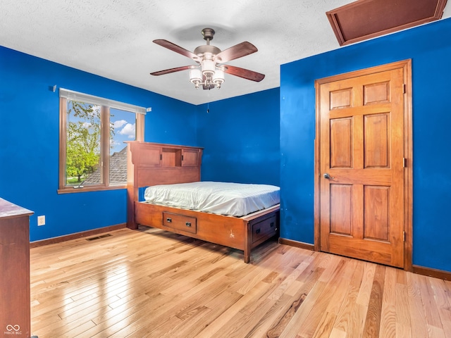 bedroom with visible vents, wood finished floors, attic access, and a textured ceiling