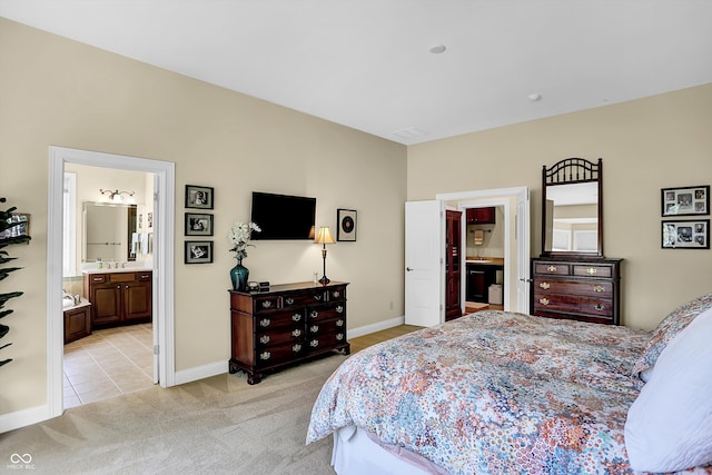 bedroom featuring baseboards, light tile patterned floors, connected bathroom, and light colored carpet