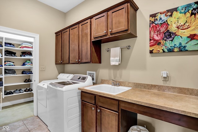 clothes washing area featuring cabinet space, washer and dryer, a sink, and light tile patterned flooring