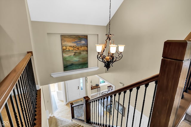 staircase with high vaulted ceiling, wood finished floors, and an inviting chandelier