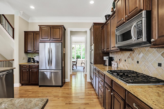 kitchen with stainless steel appliances, light wood finished floors, dark brown cabinets, and crown molding