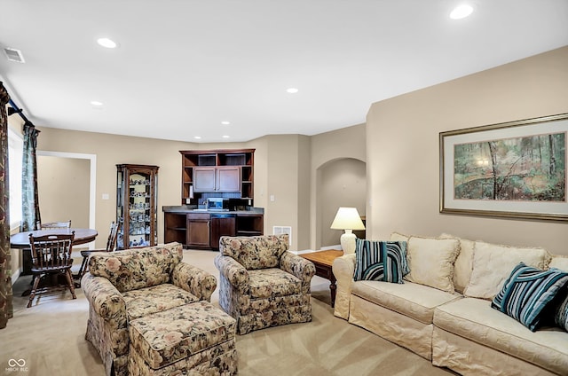 living area featuring light carpet, visible vents, arched walkways, and recessed lighting