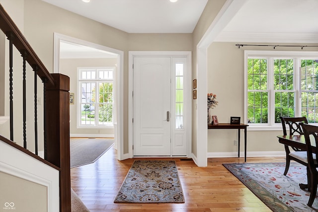 entrance foyer featuring light wood-style floors, stairway, and baseboards