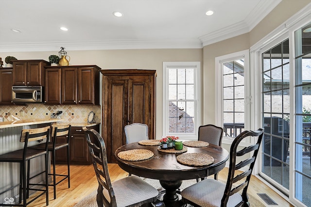 dining space featuring light wood-style flooring, visible vents, crown molding, and recessed lighting