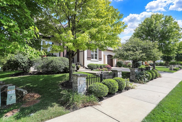 view of front facade featuring concrete driveway, a front lawn, and a fenced front yard