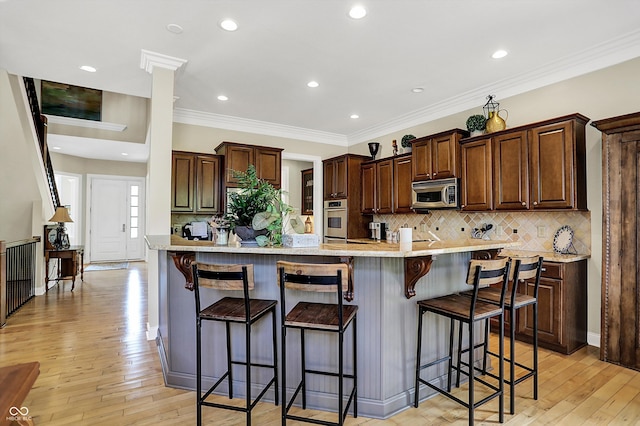 kitchen with stainless steel appliances, a breakfast bar area, and light wood finished floors