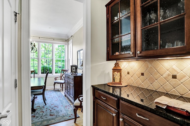 kitchen featuring glass insert cabinets, crown molding, backsplash, and dark brown cabinetry