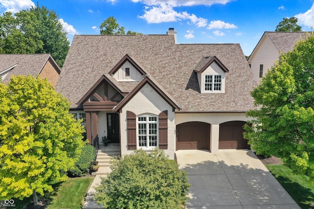 view of front of property with a garage, concrete driveway, a chimney, roof with shingles, and brick siding