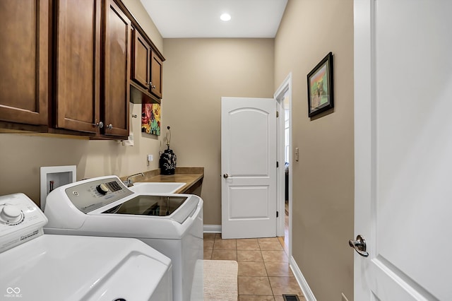 laundry room with cabinet space, light tile patterned floors, baseboards, washing machine and dryer, and a sink