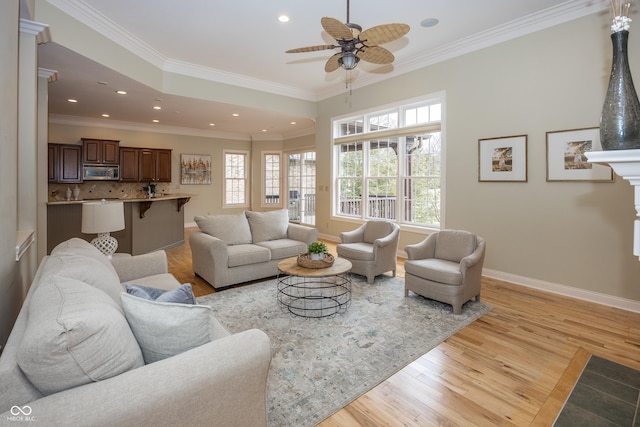 living area with light wood-style flooring, recessed lighting, a ceiling fan, baseboards, and ornamental molding