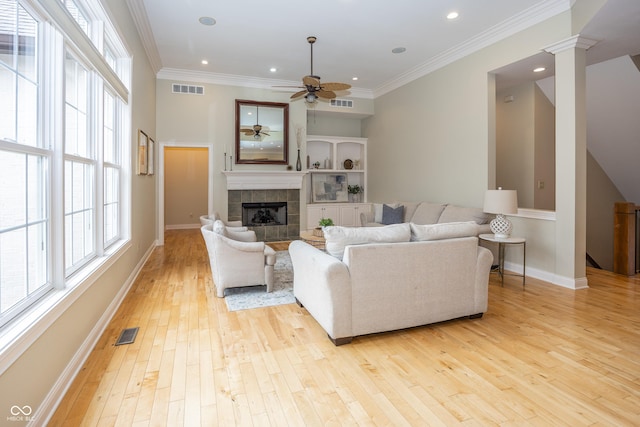 living area featuring ornamental molding, visible vents, decorative columns, and light wood-style flooring