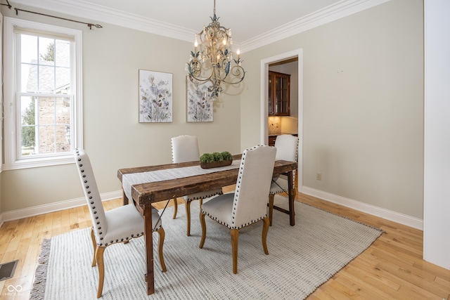 dining area featuring ornamental molding, light wood-style floors, and baseboards