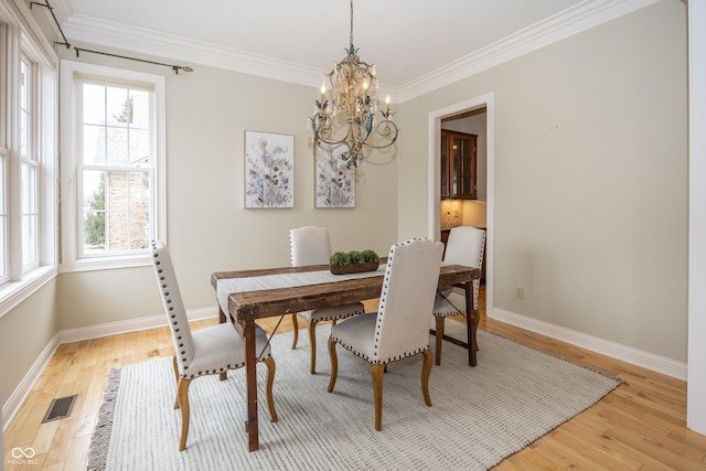 dining room featuring light wood-type flooring, baseboards, visible vents, and ornamental molding