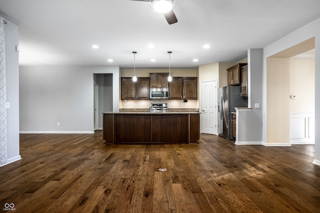 kitchen with appliances with stainless steel finishes, decorative light fixtures, dark hardwood / wood-style floors, and ceiling fan