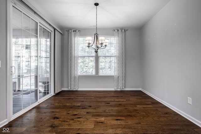 unfurnished dining area with a notable chandelier and dark hardwood / wood-style flooring