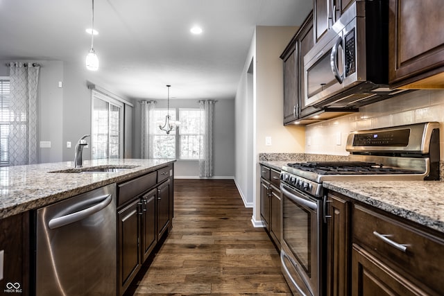 kitchen with dark hardwood / wood-style flooring, light stone countertops, stainless steel appliances, and pendant lighting