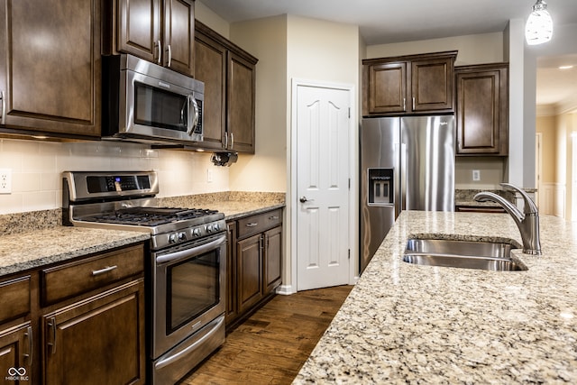 kitchen with sink, light stone countertops, dark wood-type flooring, and stainless steel appliances