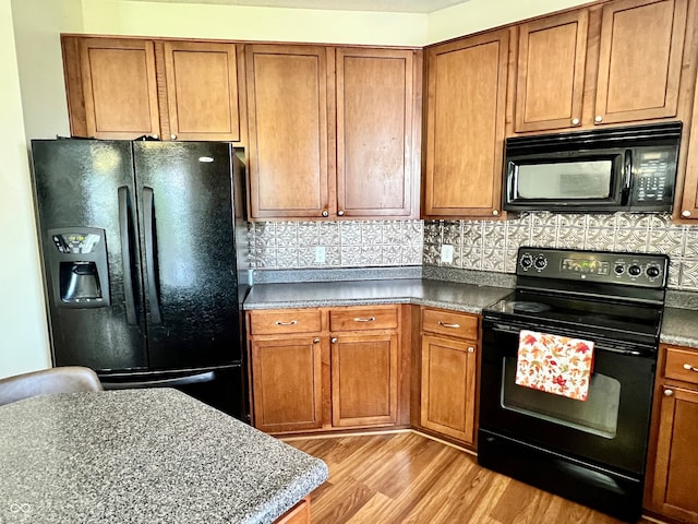 kitchen featuring black appliances, light hardwood / wood-style flooring, and decorative backsplash