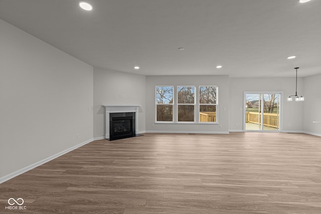 unfurnished living room with a chandelier and light hardwood / wood-style floors