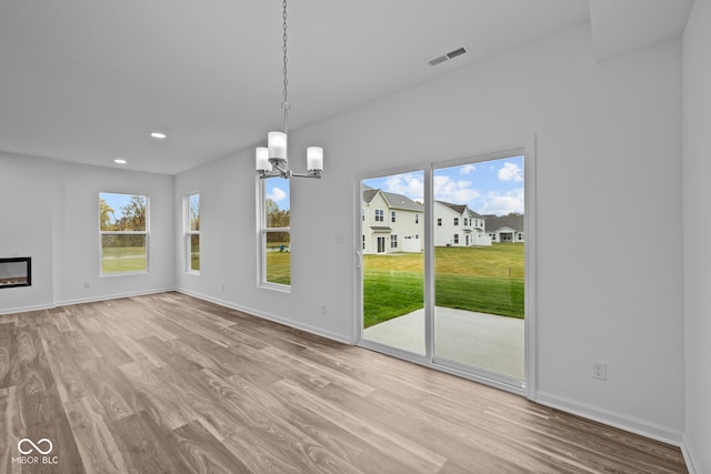 unfurnished dining area with light hardwood / wood-style floors and a notable chandelier