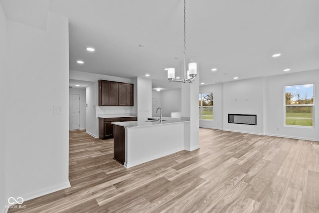 kitchen with a healthy amount of sunlight, light hardwood / wood-style floors, sink, and decorative light fixtures