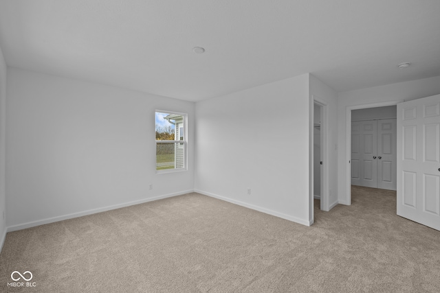 unfurnished bedroom with light colored carpet and a closet