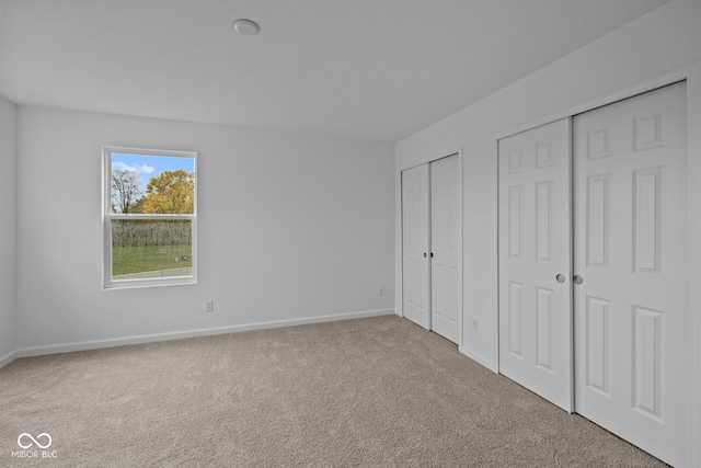 unfurnished bedroom with multiple closets and carpet floors