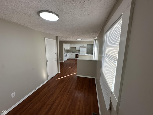 corridor featuring plenty of natural light, a textured ceiling, and dark hardwood / wood-style flooring