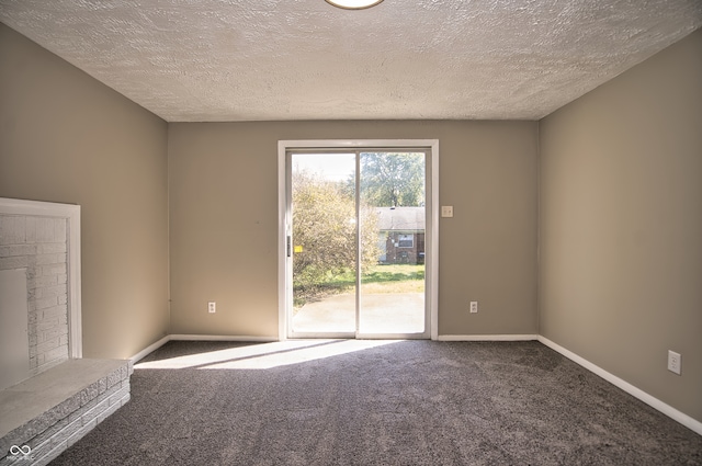 carpeted spare room featuring a textured ceiling and a fireplace