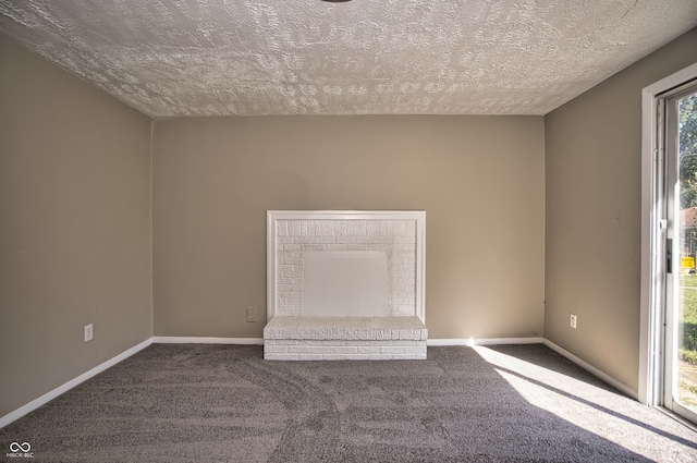 carpeted empty room featuring a textured ceiling and a fireplace