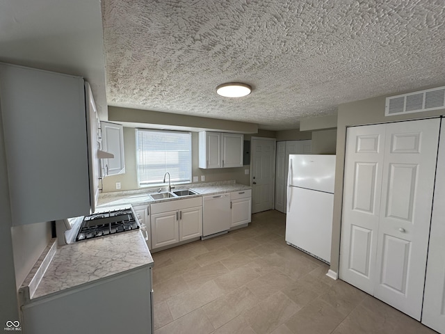 kitchen with sink, white appliances, and a textured ceiling