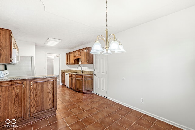 kitchen featuring pendant lighting, sink, white appliances, light stone countertops, and an inviting chandelier