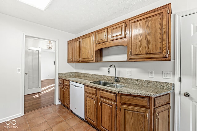 kitchen with dishwasher, light stone countertops, sink, and light tile patterned flooring