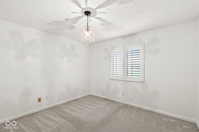 carpeted empty room featuring a chandelier and a textured ceiling